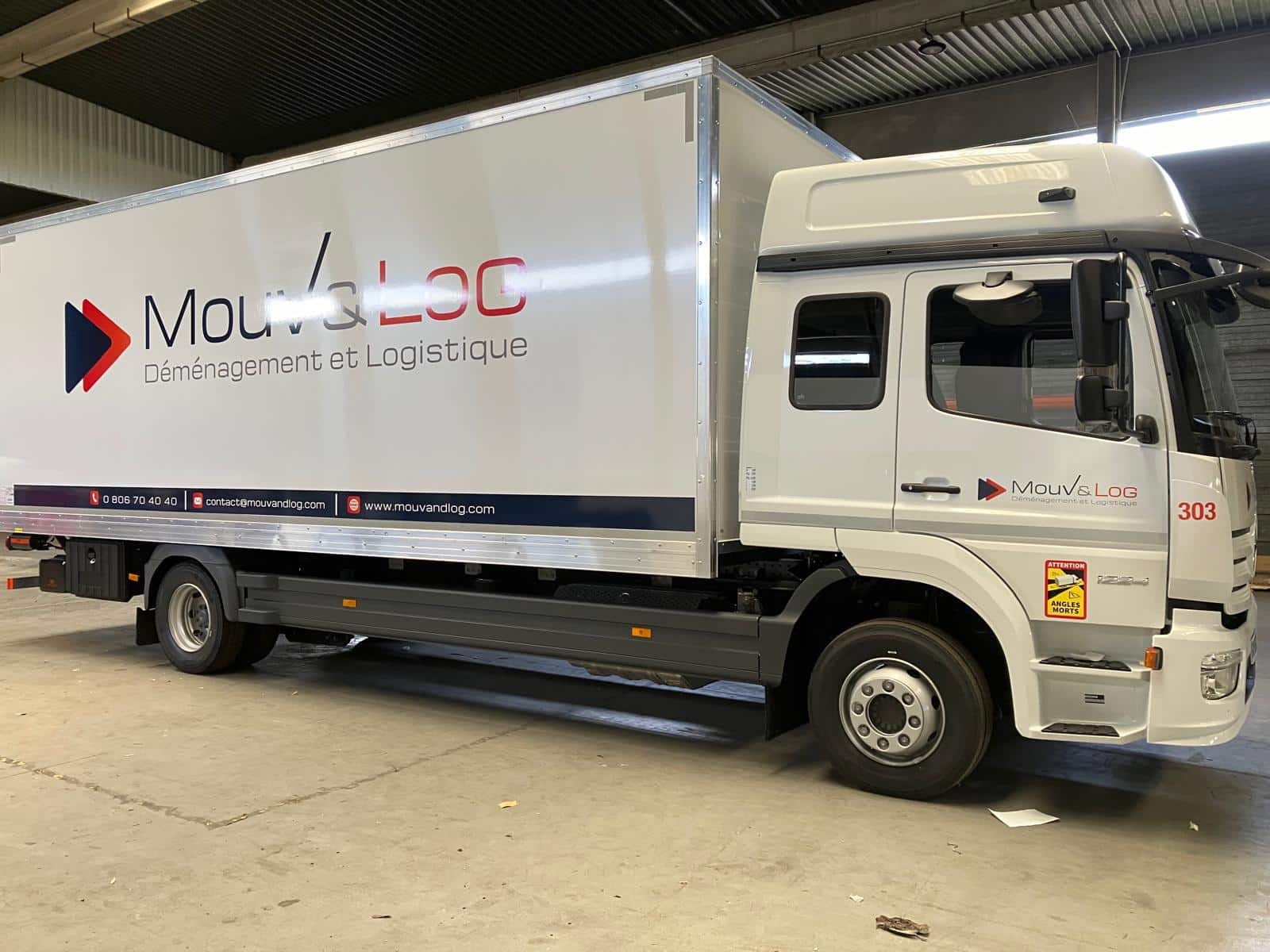 Camion blanc Mouv & LOG pour déménagement et logistique. Texte: 0806704040, contact@mouvandlog.com, www.mouvandlog.com. Signalétique Angles Morts, n° 303.