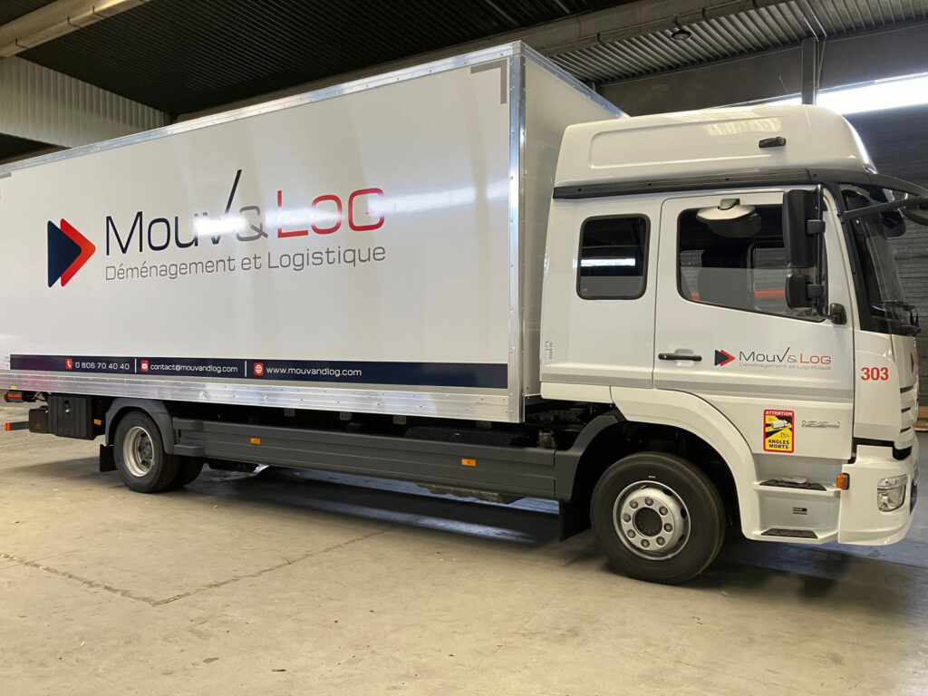Camion blanc Mouv & LOG de déménagement et logistique, logo. Infos contact et avertissement "Angles Morts" visibles sur le véhicule.